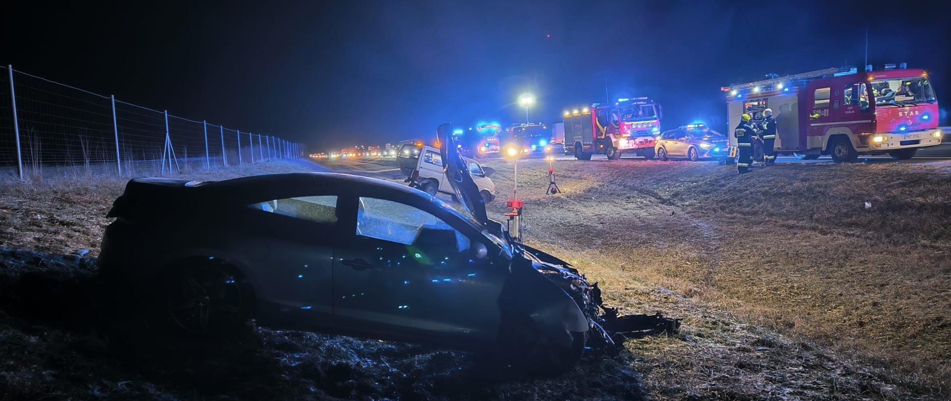 Uszkodzone Renault. w tle służby ratunkowe.