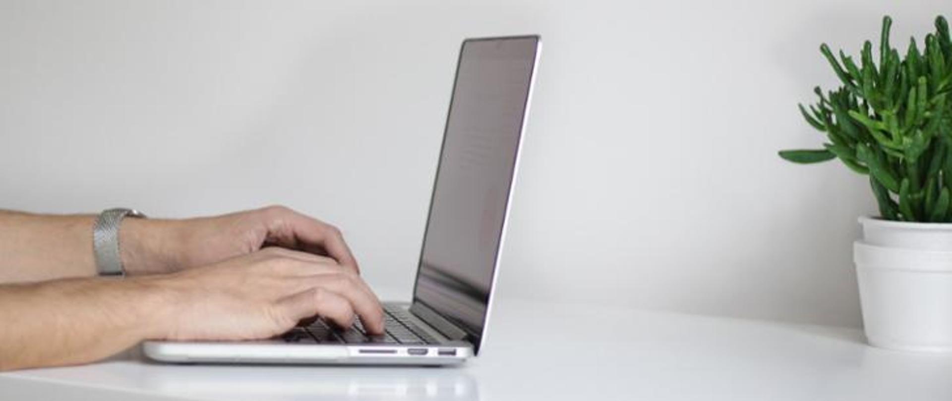 Ręce osoby, która pisze na laptopie.