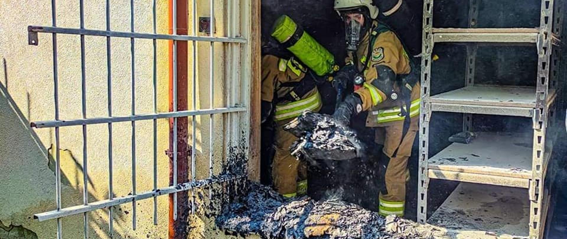 Strażacy wyrzucają przez okno spalone dokumentu.