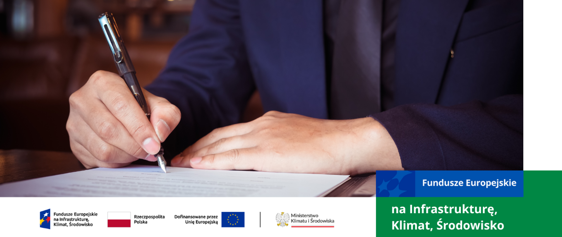 Stół, na nim dokument który jest podpisywany przez mężczyznę. Zbliżenie na jego ręce. W jednym ręku pióro wietrzne.