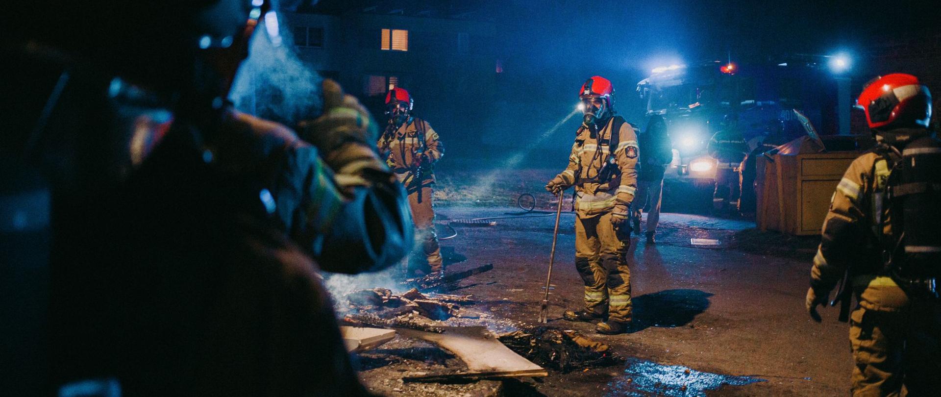 Podsumowanie zdarzeń w dniach 21.03 - 27.03.2022 r. - zdjęcie przedstawia strażaków ubranych w sprzęt ochrony układu oddechowego podczas dogaszania pożaru