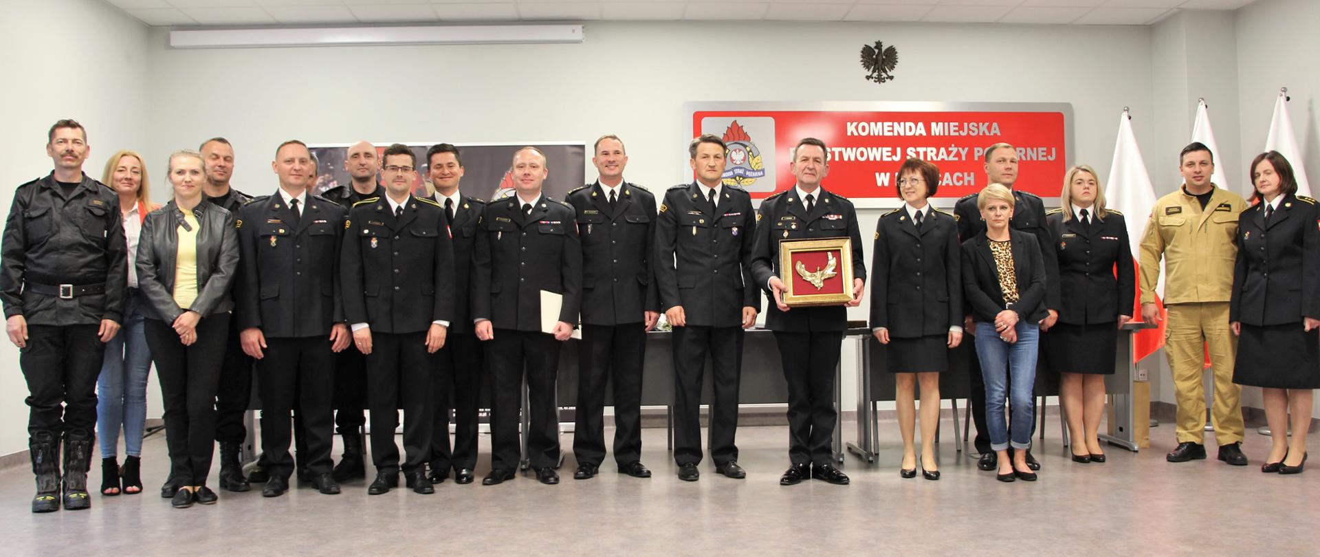 Na zdjęciu przedstawiono zgromadzonych funkcjonariuszy i pracowników cywilnych Komendy Miejskiej Państwowej Straży Pożarnej w Kielcach wraz z odchodzącym komendantem, którzy żegnają przełożonego.