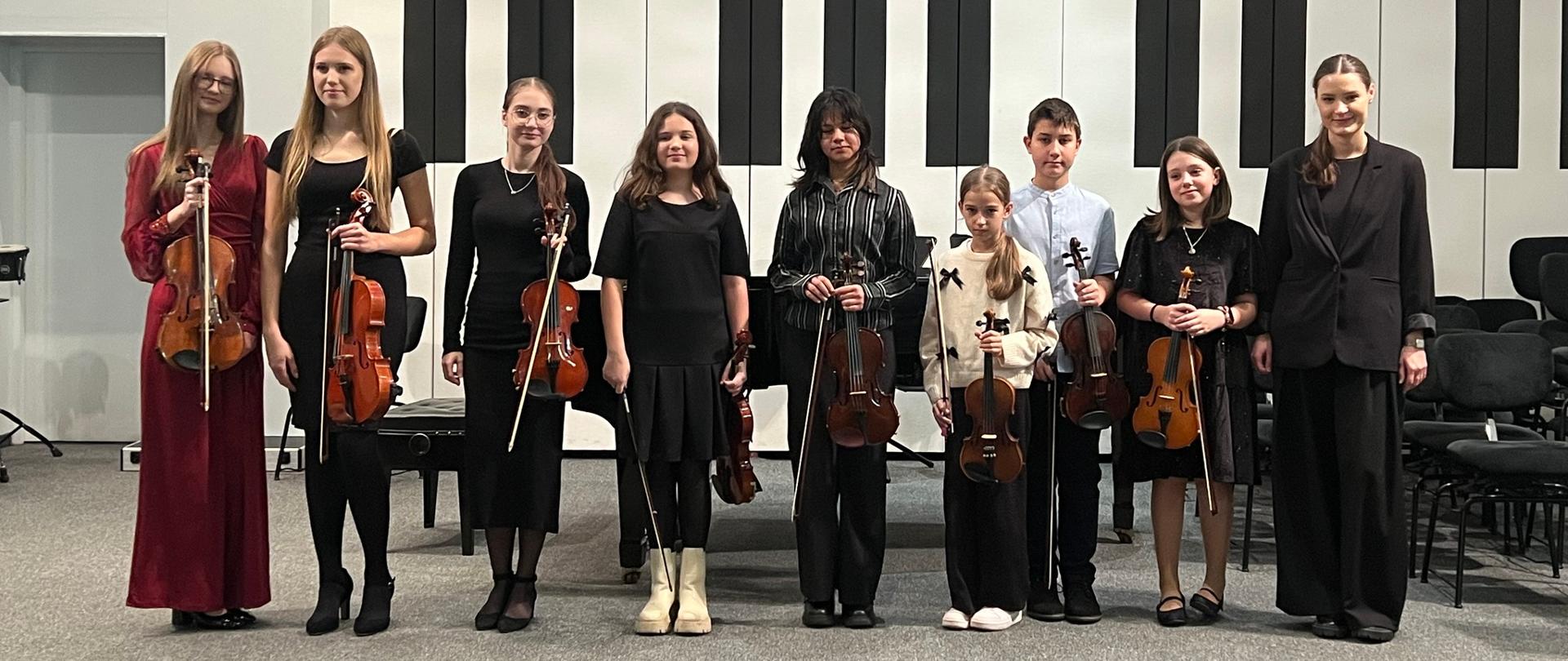 Nauczycielka stoi na scenie z uczniami.