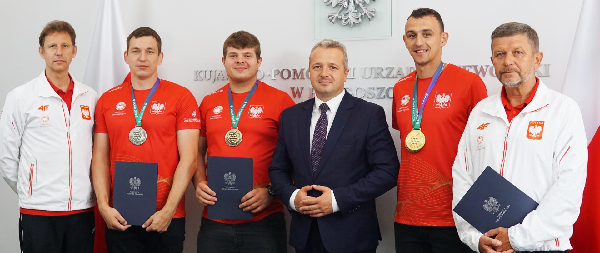Sześciu mężczyzn stojących na tle flag