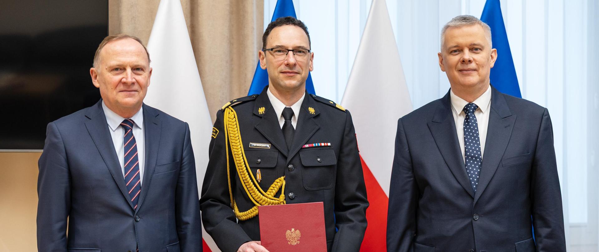 Pamiątkowa fotografia po wręczeniu nominacji. Nadbrygadier Wojciech Kruczek stoi w centrum, trzymając dokument powołania, obok niego przedstawiciele kierownictwa MSWiA.