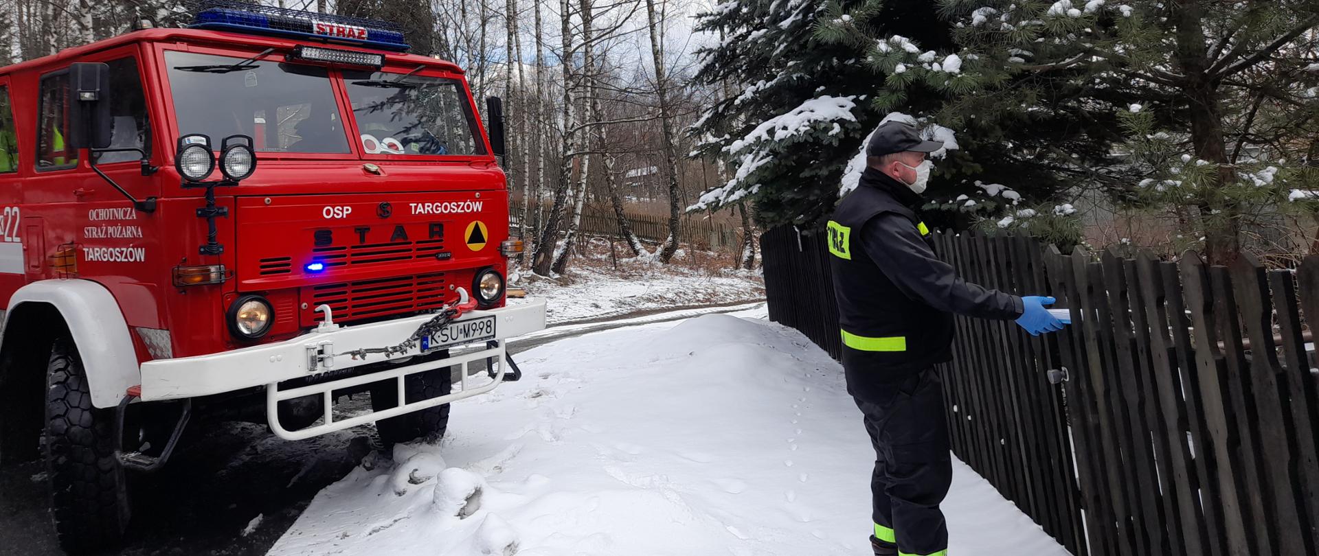 Zdjęcie przedstawia strażaka biorącego udział w akcji roznoszenia ulotek.