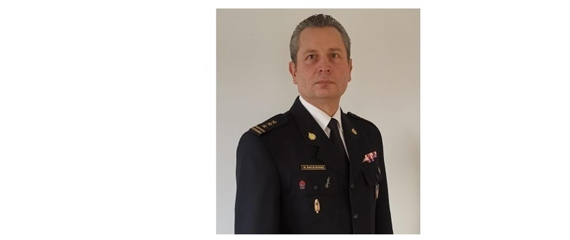 Komendant Powiatowy Państwowej Straży Pożarnej w Wołowie st. bryg. Wojciech Maciejewski na jasnym tle w mundurze galowym. 