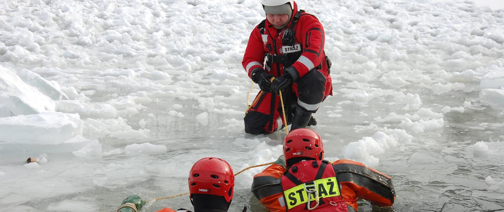 Ratownicy w przerębli, jeden ratownik próbuje wyciągnąć ich na taflę lodu 