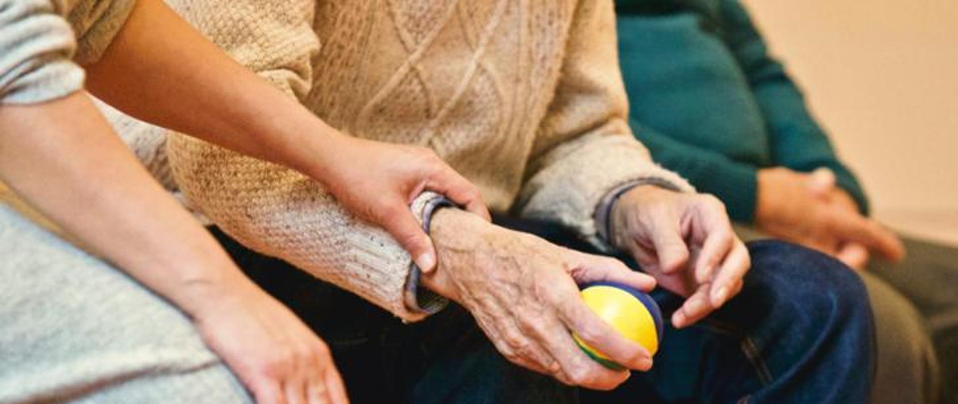 Starsza kobieta trzyma w dłoni małą piłkę