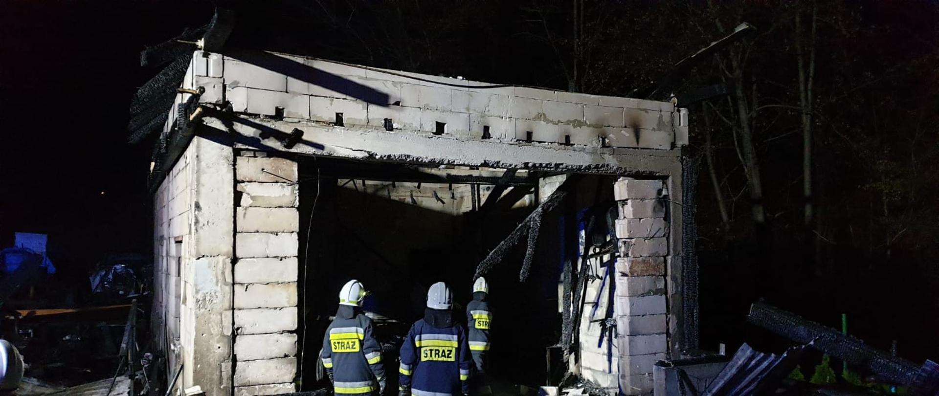 Strażacy stojący obok ścian spalonego garażu