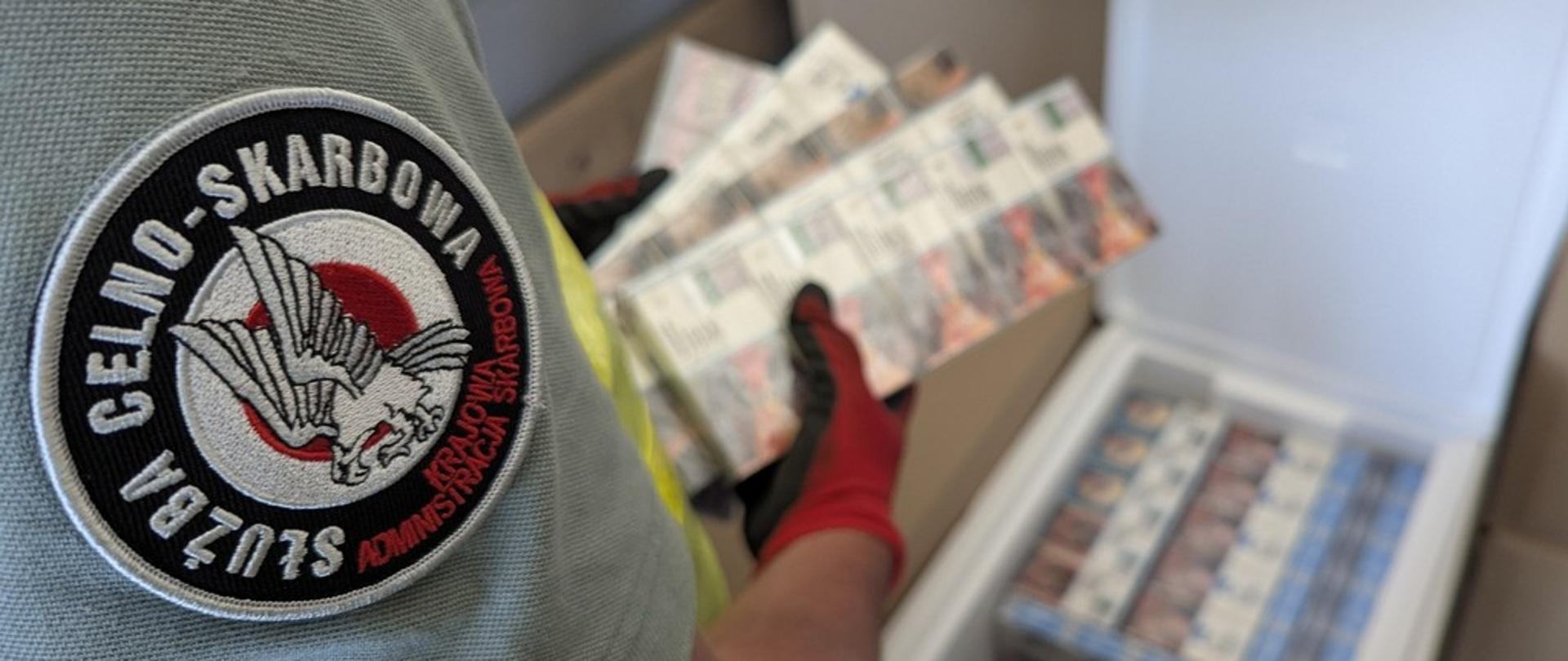 Funkcjonariusz trzyma wykryte papierosy