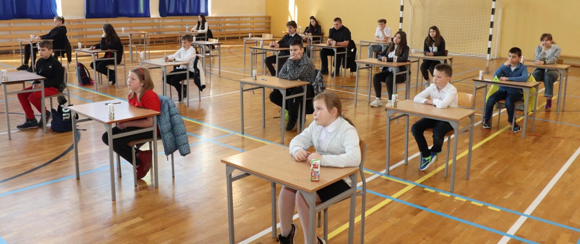 Zdjęcie przedstawiające młodzież na sali gimnastycznej przygotowana do pisania testu wiedzy 