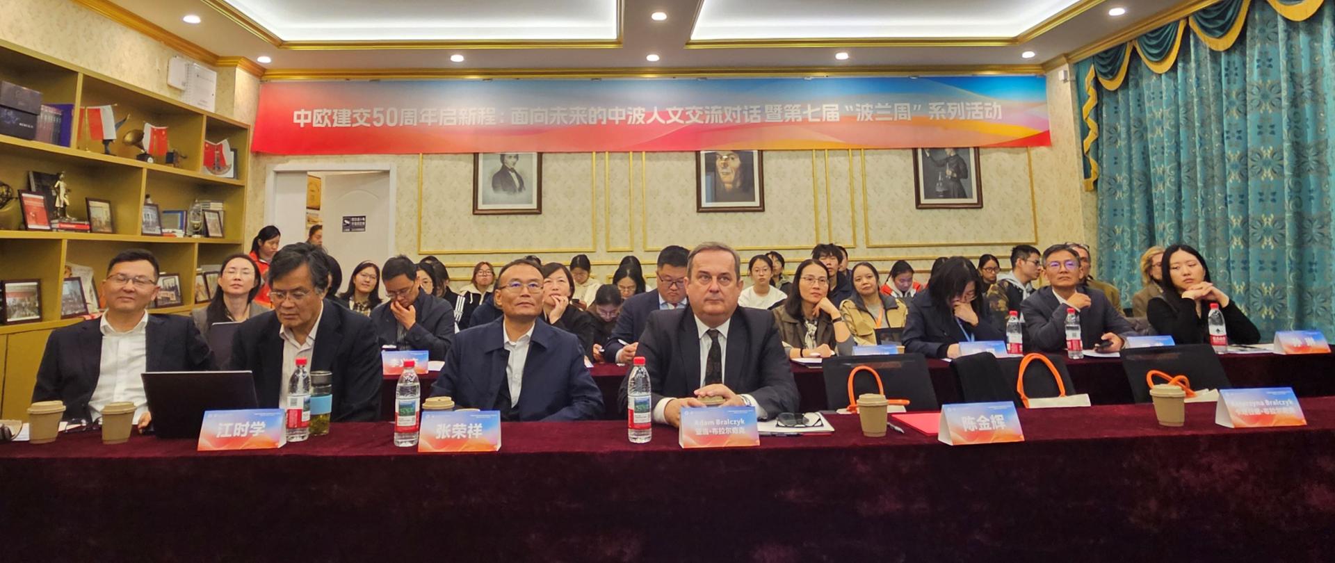 ludzie siedzą w ławkach w sali 