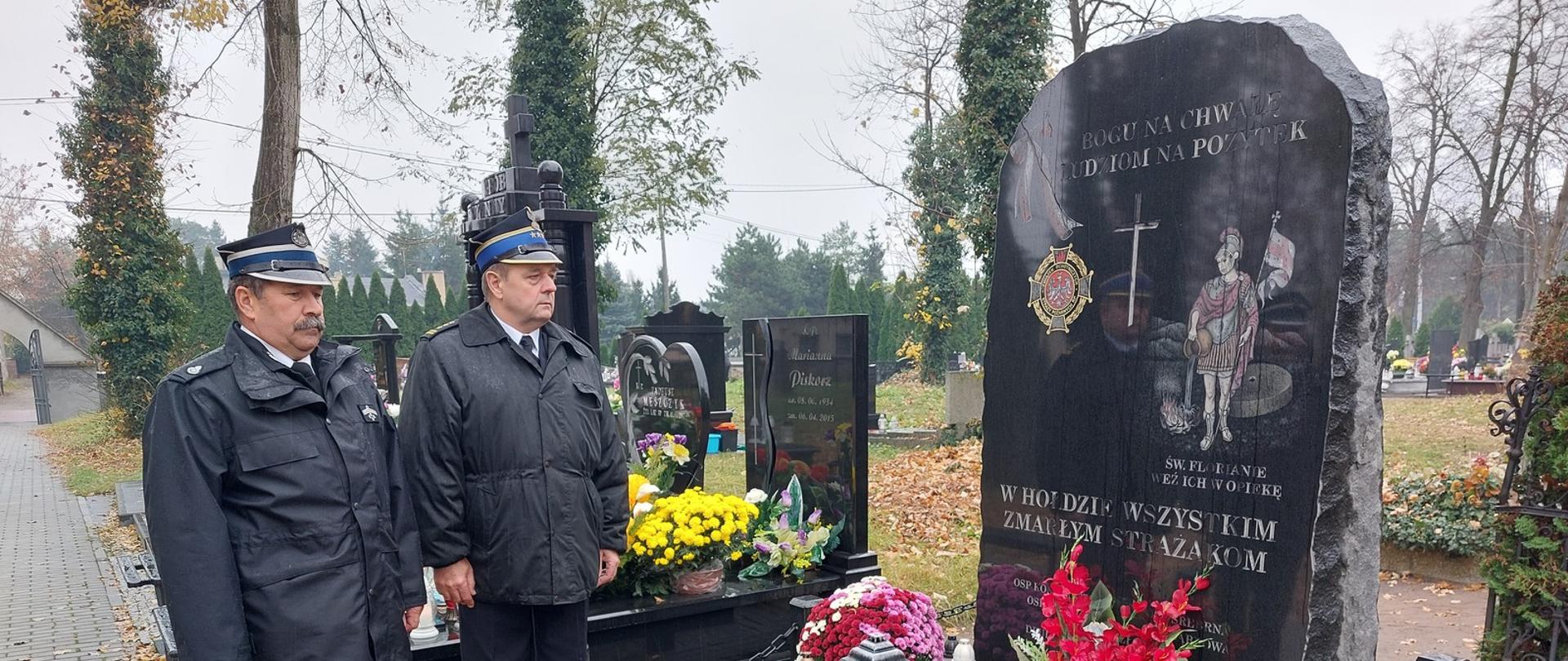 Zdjęcie przedstawia Komendanta Powiatowego PSP w Pabianicach oraz Prezesa ZOP ZOSP RP w Pabianicach stojących przed pomnikiem upamiętniającym wszystkich zmarłych strażaków. U podstawy pomnika znajdują się zapalone znicze.