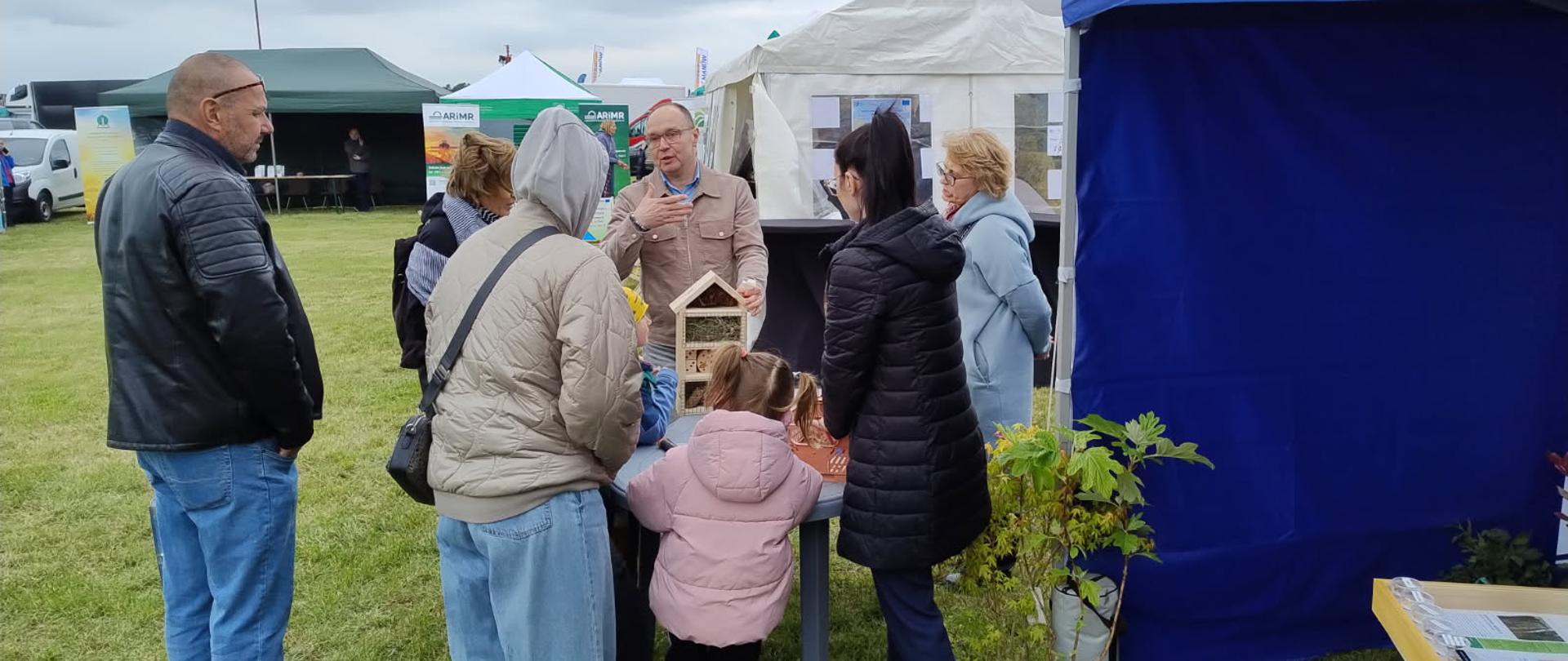 Zdjęcie przedstawia uczestników warsztatów składających domek dla owadów