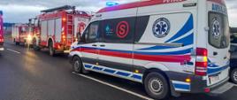 Na zdjęciu czerwone samochody strażackie oraz karetka pogotowia ratunkowego