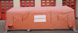 Pomarańczowy pneumatyczny namiot strażacki z napisem PSP SZAMOTUŁY na białym tle.