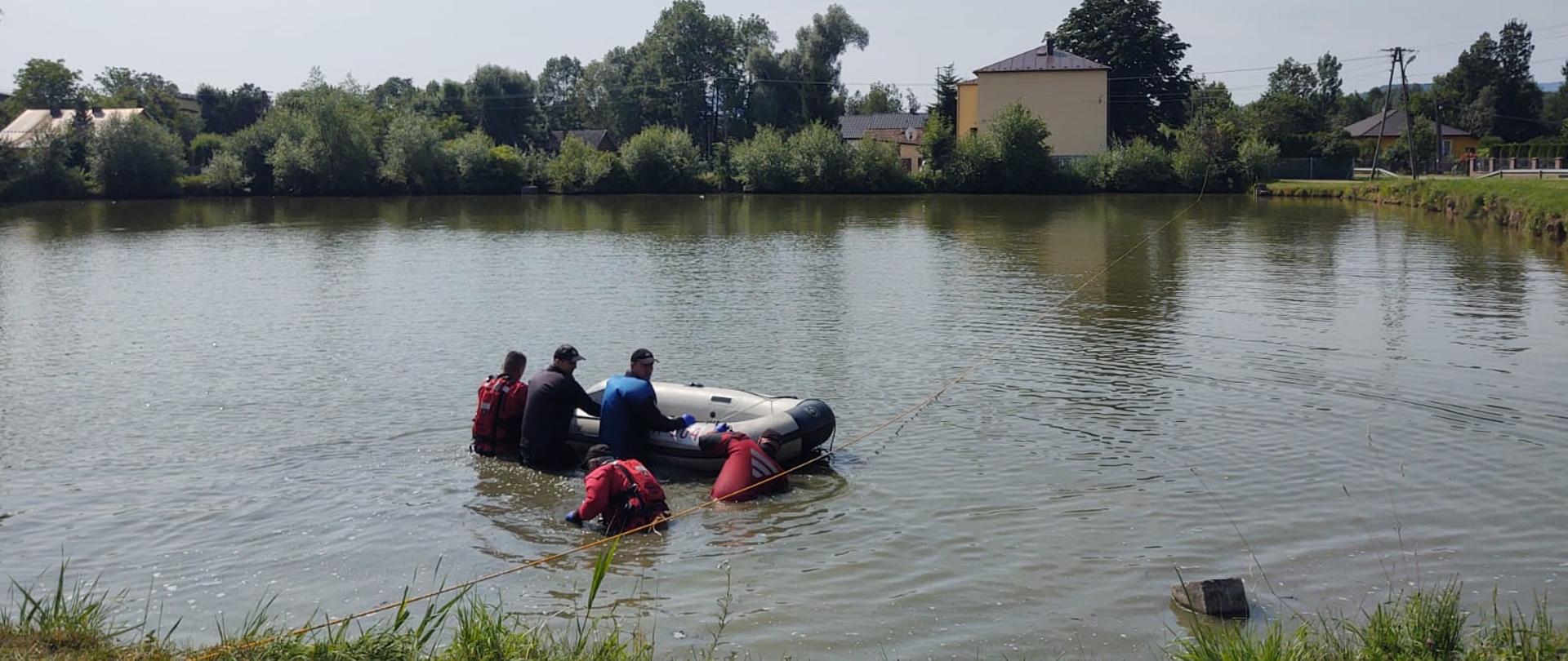 Strażacy obok pontonu na stawie