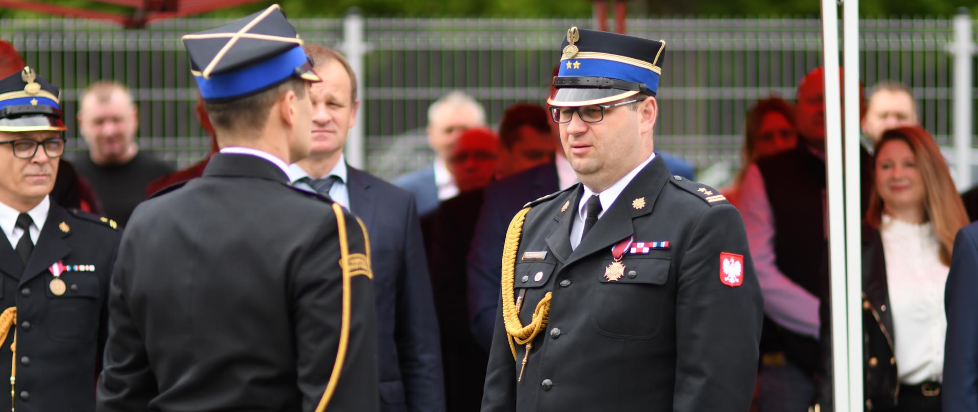 strazak stoi na przeciwko drugiego strażaka, oby dwoje na baczność. składanie meldunku,