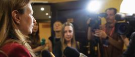 Minister funduszy i polityki regionalnej Katarzyna Pełczyńska-Nałęcz stoi przez dziennikarzami z mikrofonami i kamerami