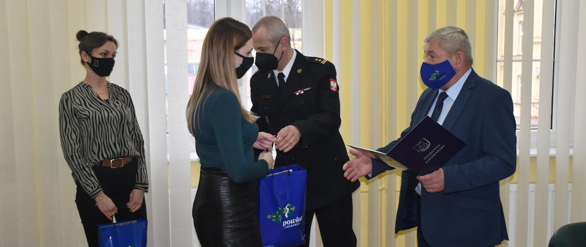 Zdjęcie przedstawia zastępce KP PSP w Lidzbarku Warmińskim oraz Starostę, który wręcza czujki mieszkance pow. lidzbarskiego