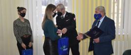 Zdjęcie przedstawia zastępce KP PSP w Lidzbarku Warmińskim oraz Starostę, który wręcza czujki mieszkance pow. lidzbarskiego