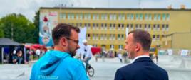 2 mężczyzn, w tym wicewojewoda, stoją tyłem do obiektywu, rozmawiają, uśmiechają się 