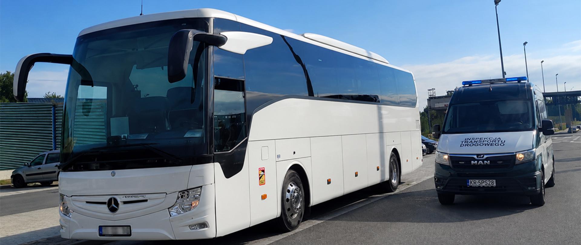 Biały autokar zatrzymany do kontroli przez ITD, obok pojazdu stoi samochód służbowy inspektorów, kontrola odbywa się w Balicach przy autostradzie A4