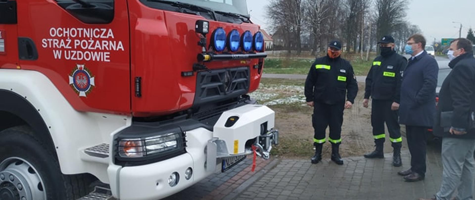 Ludzie stoją i patrzą na wóz strażacki