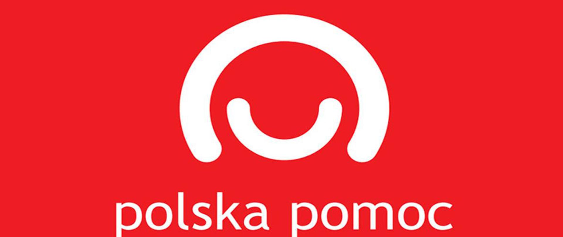 Na czerwonym tle dwa półkola w kolorze białymo różnej wielkości tworzące uśmiechniętą postać praz napis polska pomoc pod spodem