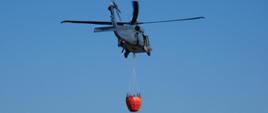 Policyjny śmigłowiec w powietrzu z podczepionym zbiornikiem bambibucket