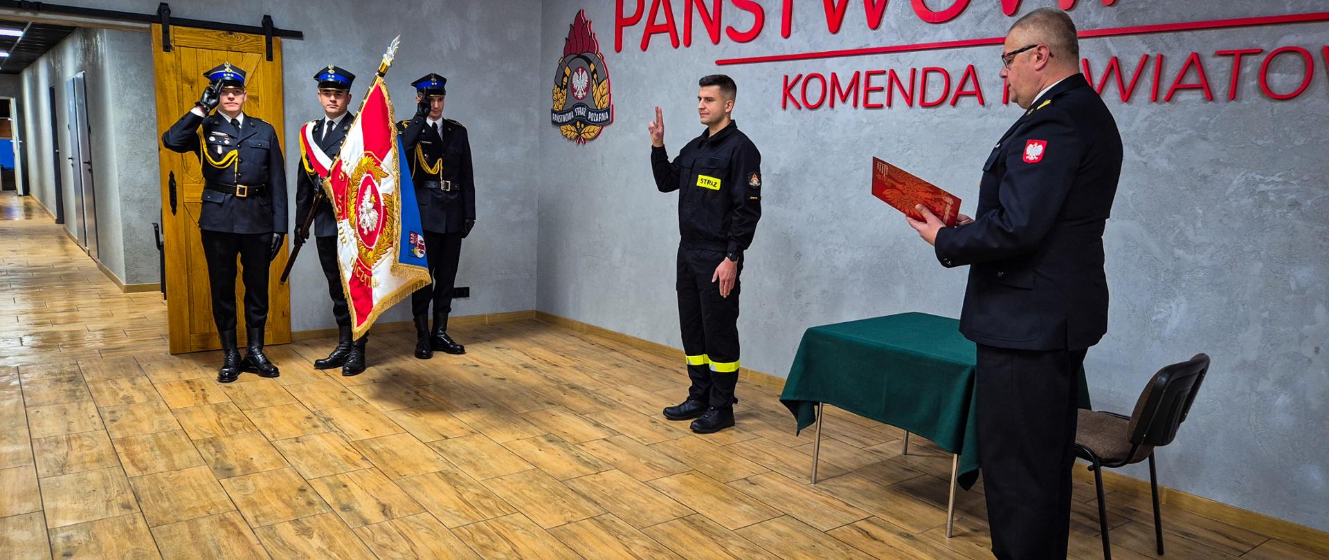 Strażak ślubuje w obecności pocztu sztandarowego i komendanta