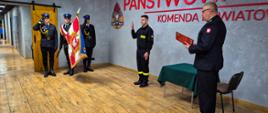 Strażak ślubuje w obecności pocztu sztandarowego i komendanta