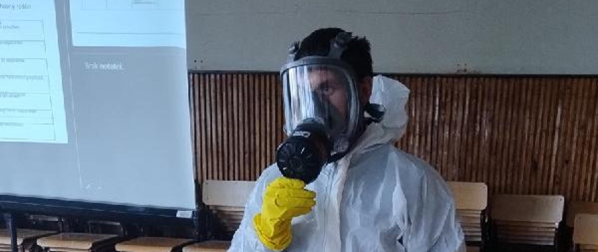 Zdjęcie przedstawia osobę w kombinezonie ochronnym i masce