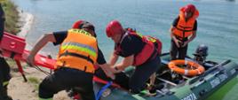 Strażacy ewakuują osobę poszkodowaną z pontonu na deskę medyczną