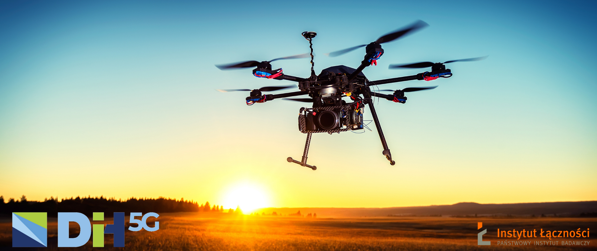 Zdjęcie drona lecącego nad polem, w tle zachód słońca