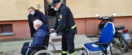 Starszy mężczyzna na wózku inwalidzkim pchanym przez strażaka