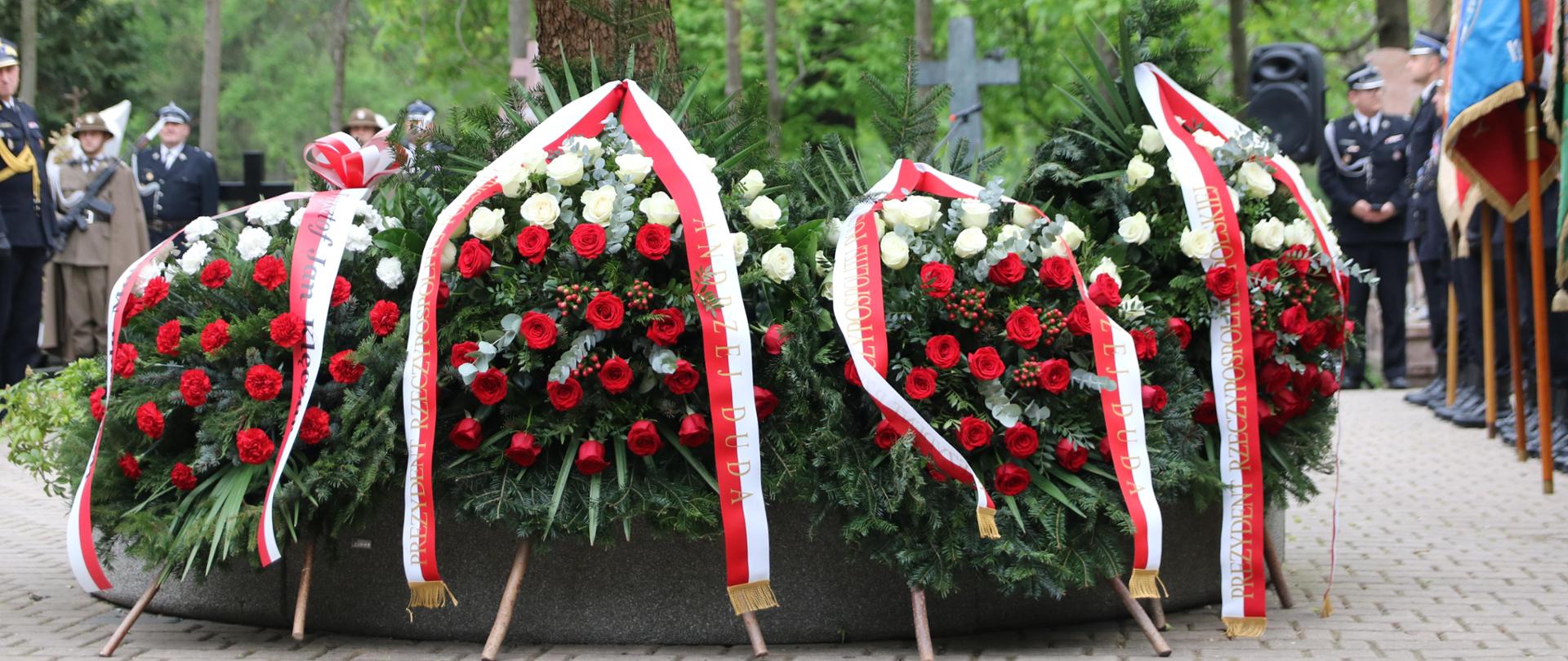 Okolicznościowe wieńce z biało- czerwonych róż, przepasane biało-czerwonymi wstążkami, na których umieszczono informację o osobie (urzędzie) składającej hołd. 