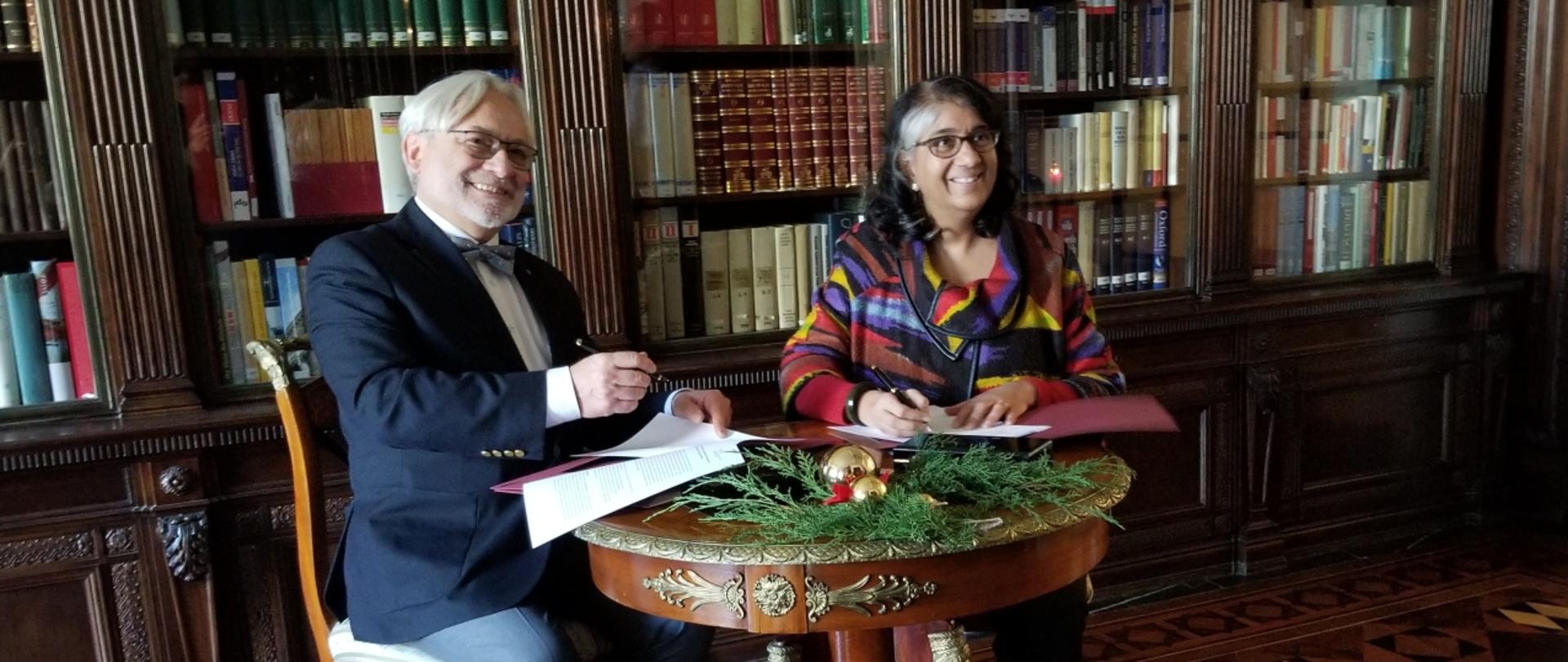 prof. Maksymowicz z prof. Shalini Randerią siedzą przy stole, za nimi półki z książkami