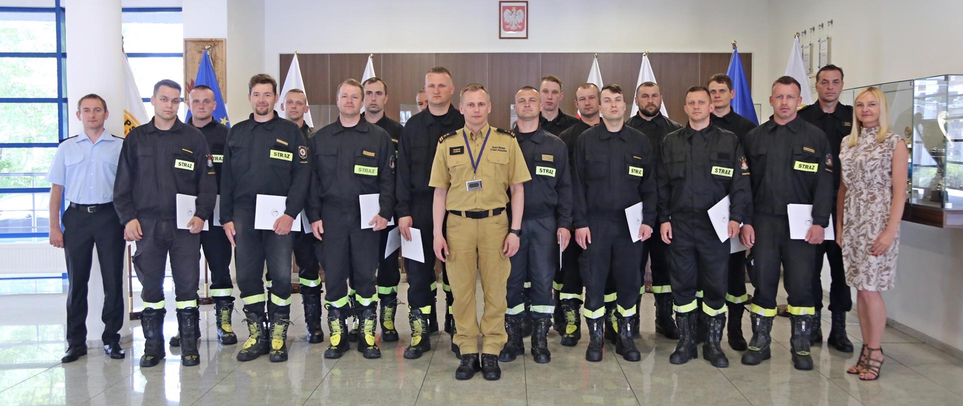 Grupowe zdjęcie uczestników szkolenia (16 funkcjonariuszy PSP) w towarzystwie Zastępcy Komendanta Centralnej Szkoły PSP, pracownicy wydziału szkoleń specjalistycznych i współpracy międzynarodowej, naczelnika wydziału technicznego oraz zastępcy wydziału szkoleń specjalistycznych i współpracy międzynarodowej