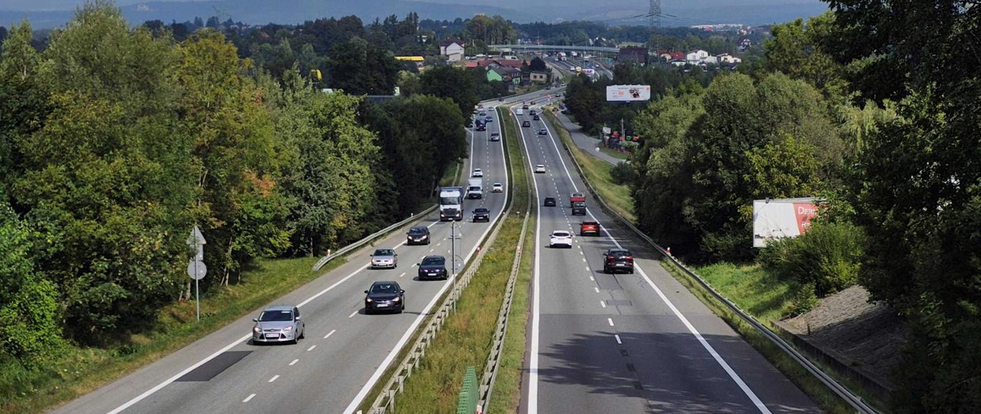 Rzut na DK7 na odcinku Kraków-Myślenice, w oddali widoczne fragmenty dróg serwisowych. Widoczna także gęsta zabudowa przy drodze oraz tereny zielone. 