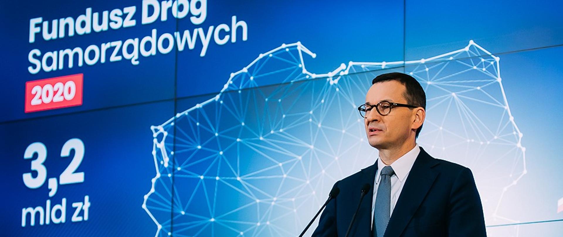 Premier Mateusz Morawiecki na tle ścianki wizyjnej: Fundusz Dróg Samorządowych.