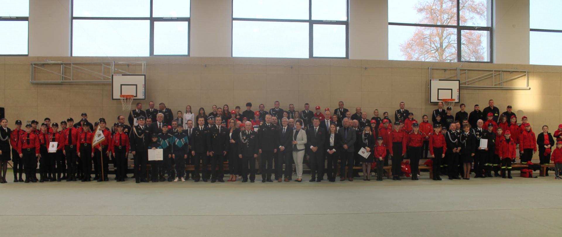 Zdjęcie przedstawia zaproszonych gości podczas wręczenia promes na dofinansowanie młodzieżowych drużyn pożarniczych