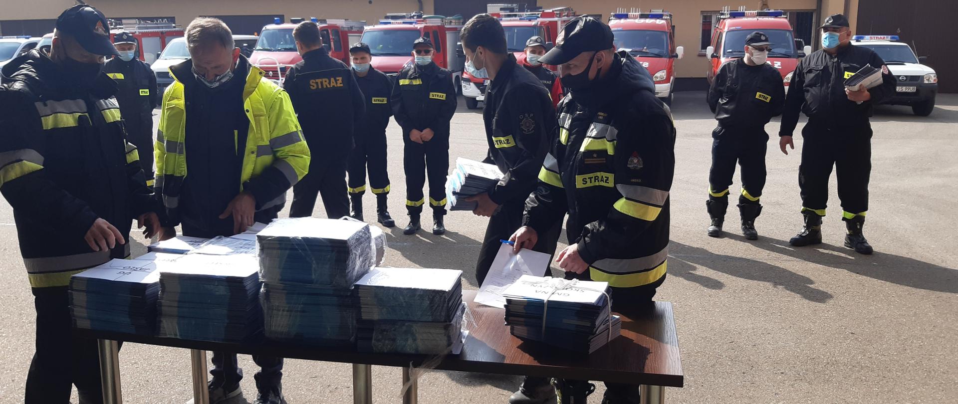 Na zdjęciu komendant młodszy brygadier Piotr Śmietana oraz zastępca komendanta powiatowego młodszy brygadier Jarosław Lula przekazują ulotki na temat szczepień druhom z ochotniczych straży pożarnych,