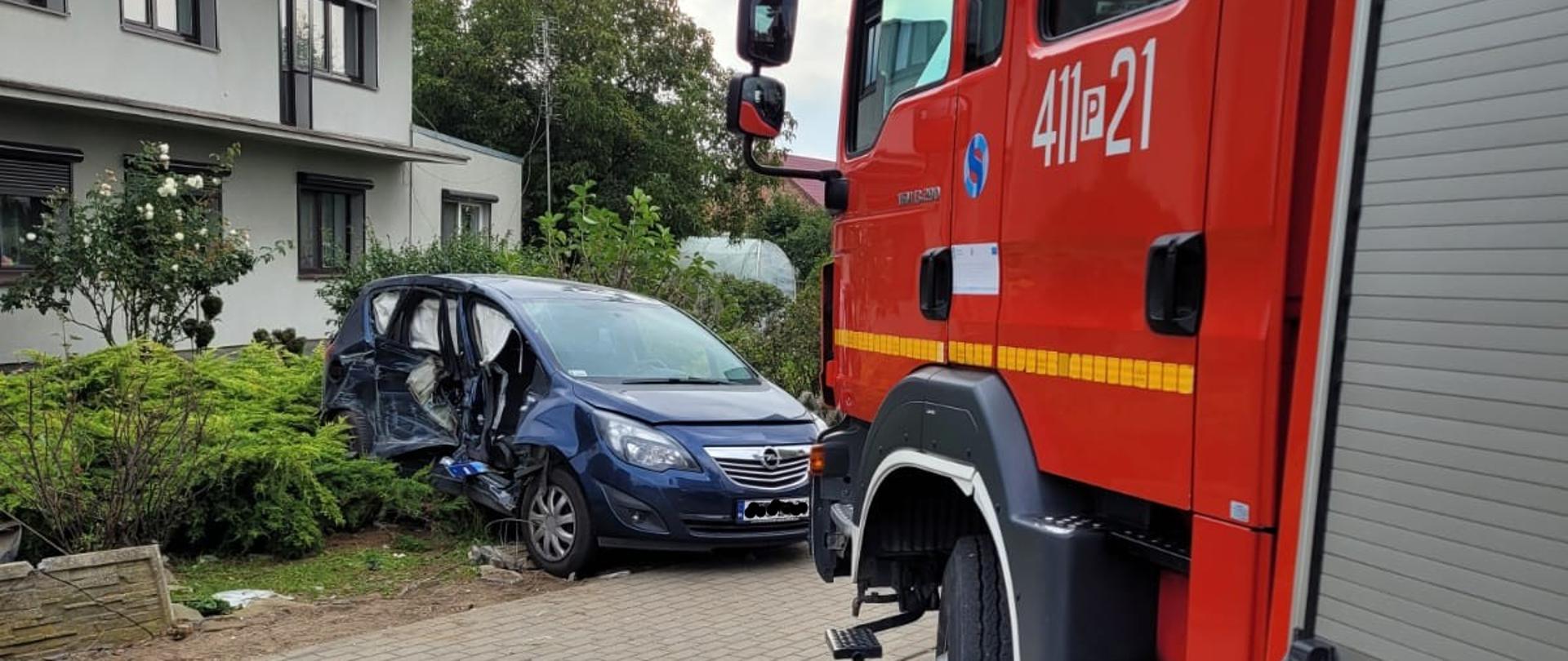Na pierwszym planie wóz bojowy JRG PSP Czarnków, w tle samochód osobowy, który po zderzeniu zjechał z drogi i uderzył w ogrodzenie posesji.