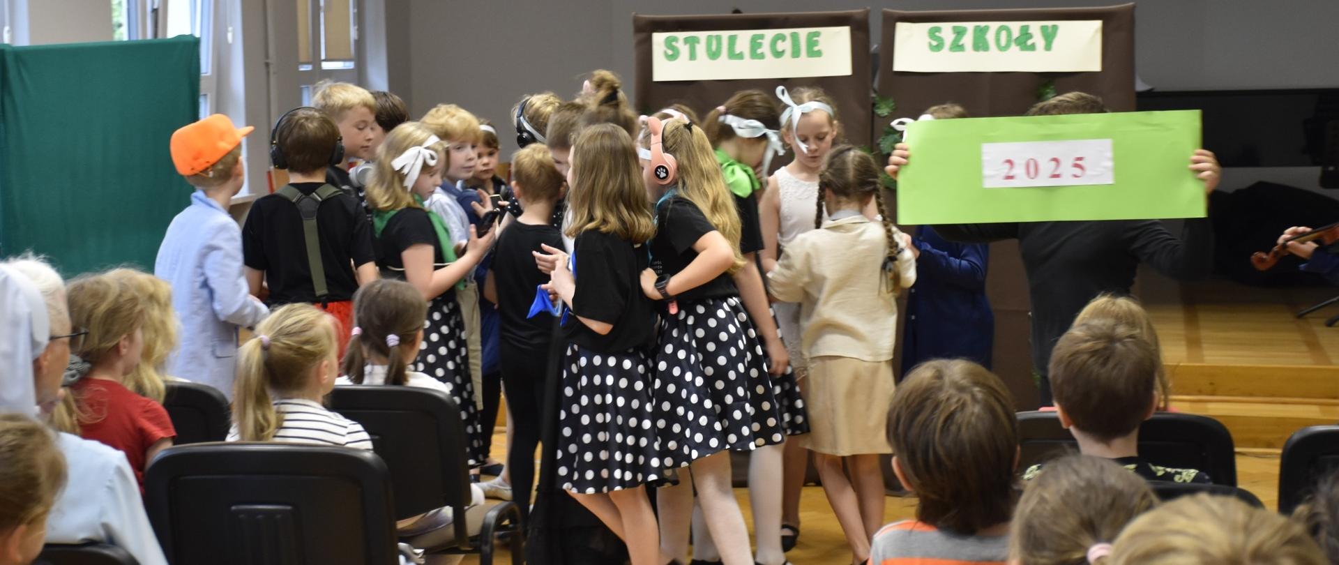 na zdjęciu widać tańczące dzieci w tle zielony na[pi stulecie szkoły dwa tysiące dwadziedzieścia pięć