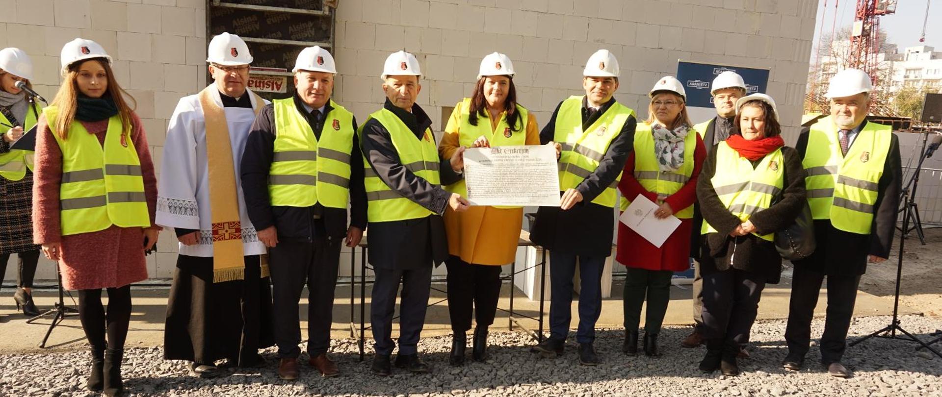 Dziesięć osób z dokumentem w tle budowa przedszkola