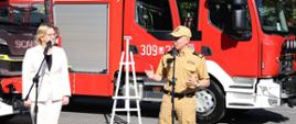 Minister Anna Moskwa przemawia w asyście Komendanta Głównego PSP na tle wozów bojowych