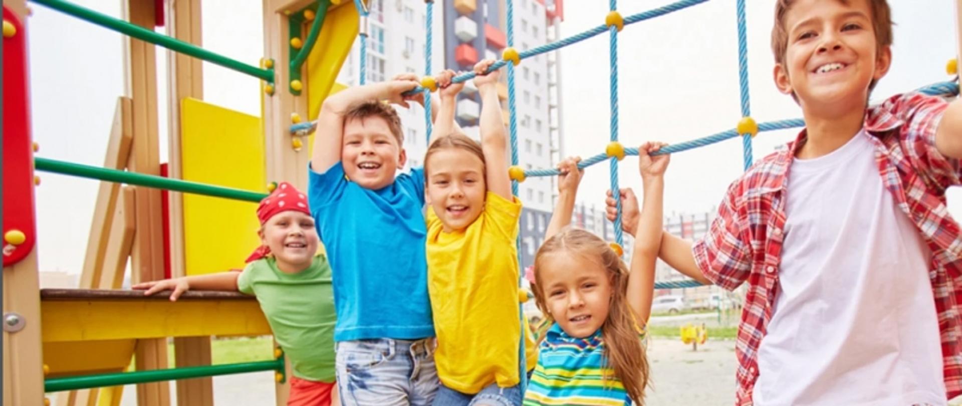 Na placu zabaw dzieci bawi się na ściance wspinaczkowej.