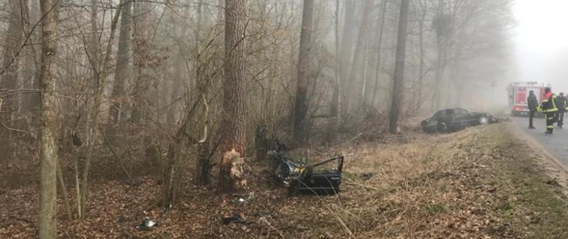 wrak samochodu biorące udział w wypadku leżący w rowie, w tle służby ratownicze